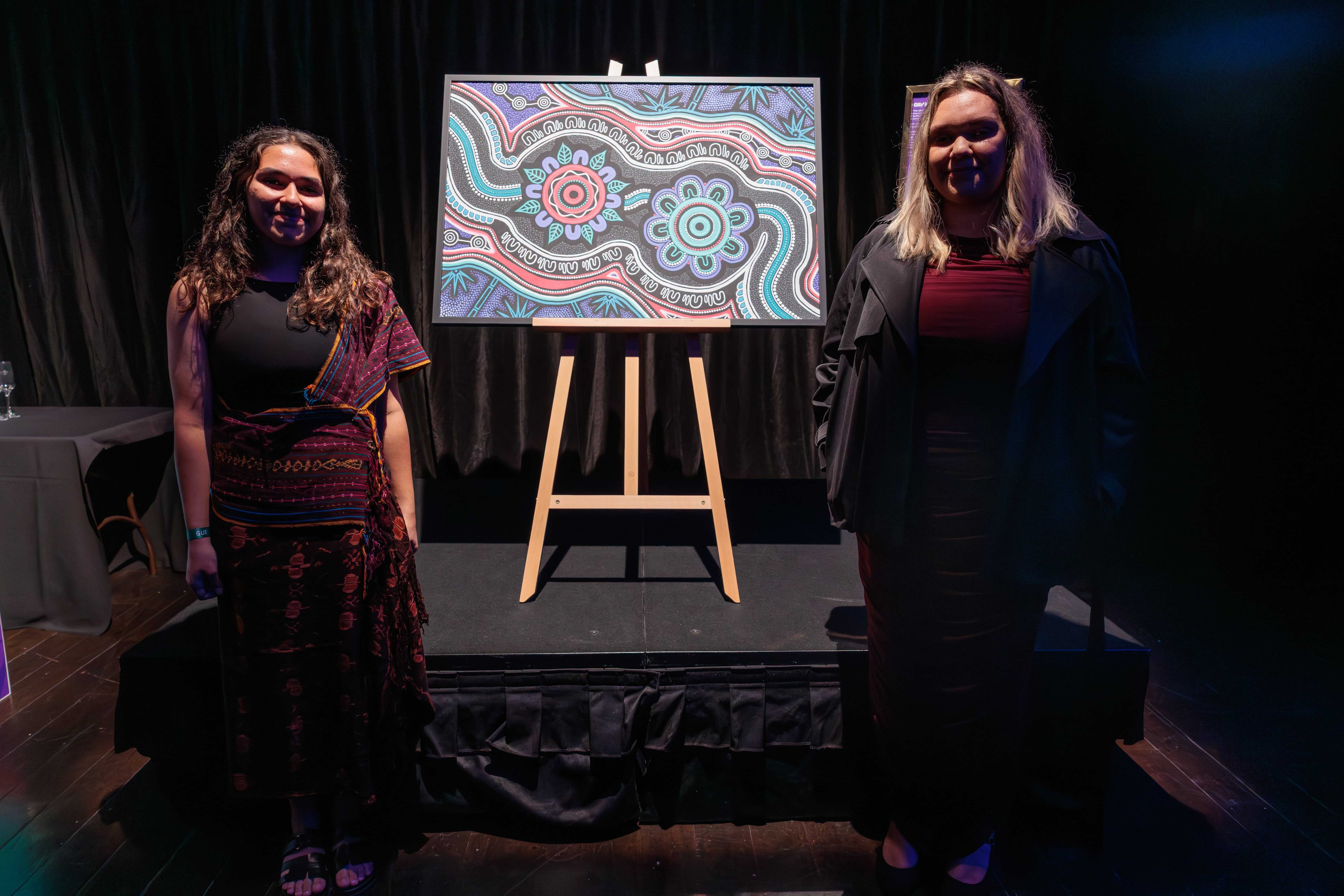 Grace Amidy and Shauna Hill pose in front of the artwork being used for the 2026 Women's Asian Cup
