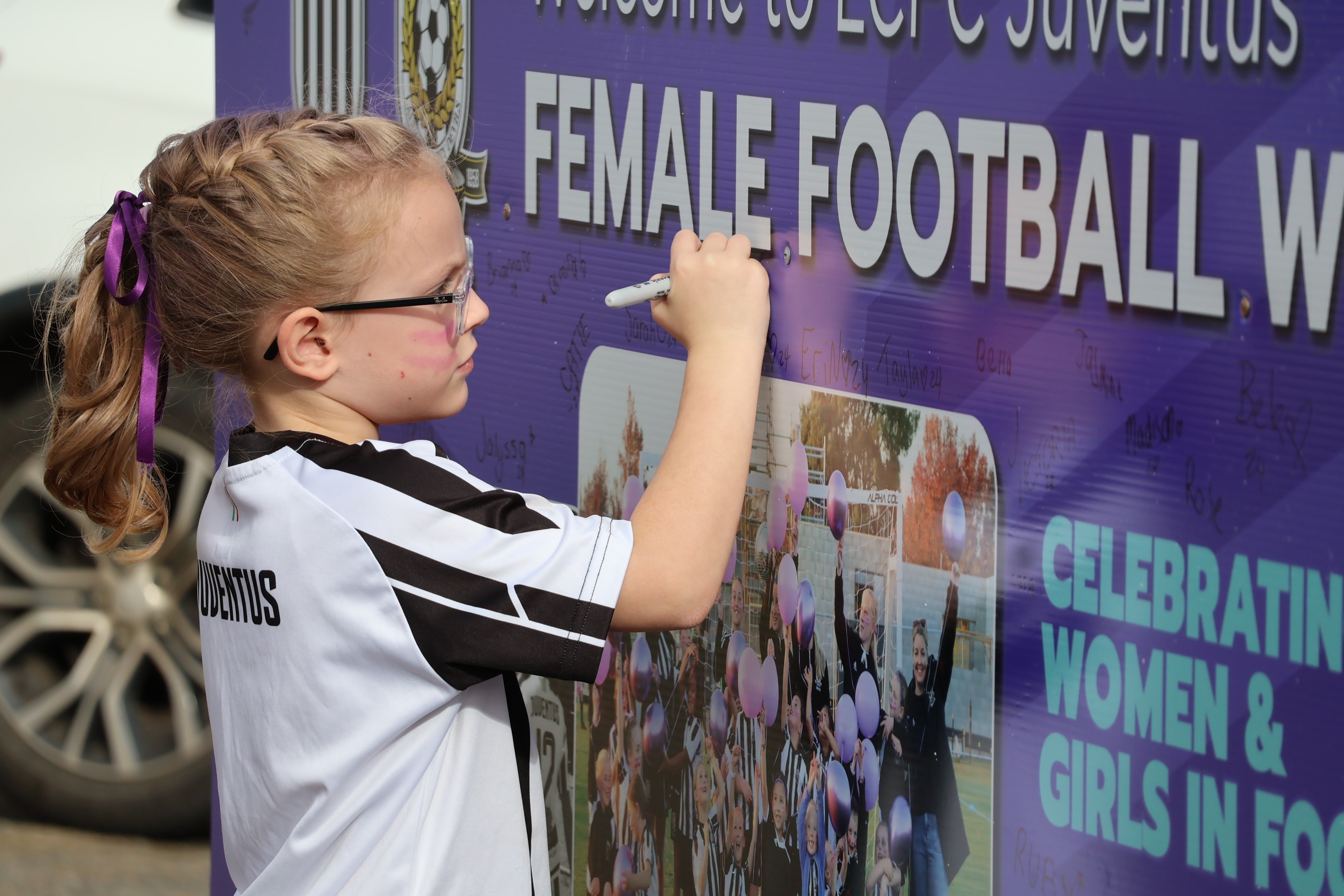 A young Launceston City FC player signing a Female Football Week poster (photo supplied by Jess Woodroffe)